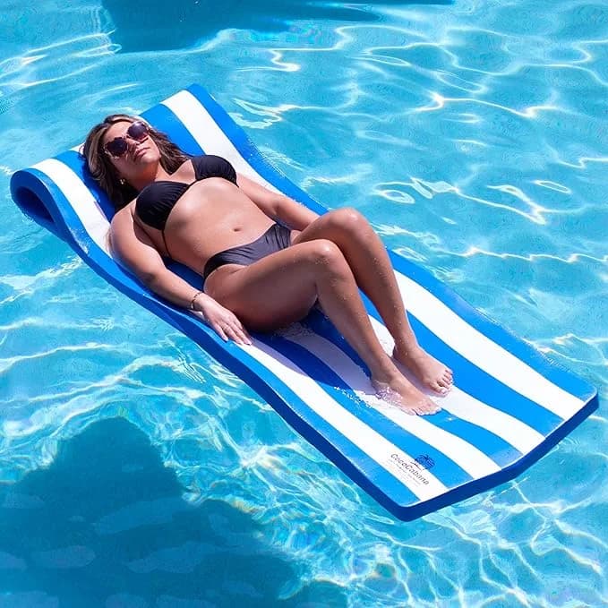 Woman relaxing on a Cococabana 74-inch striped blue and white foam pool float with headrest in a clear blue swimming pool